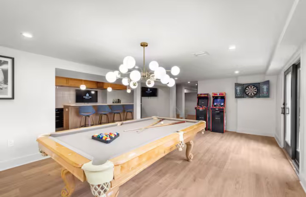 Game room with pool table, arcade machines, and bar