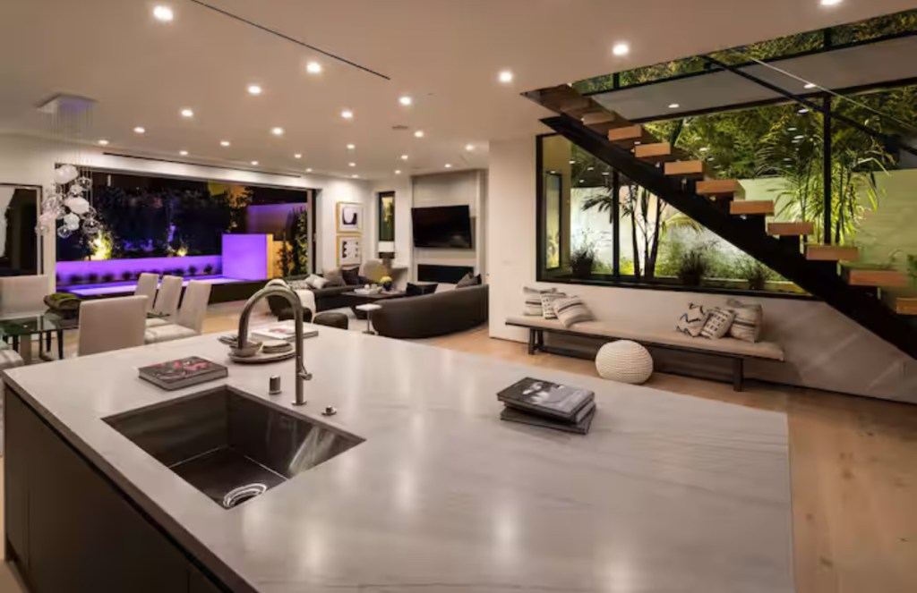 Open kitchen and living room at night with lit pool